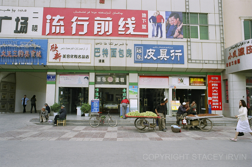 Uighurs sell grapes and dates in front of modern Chinese shops on the edge of the Han part of town in
Kashgar.
